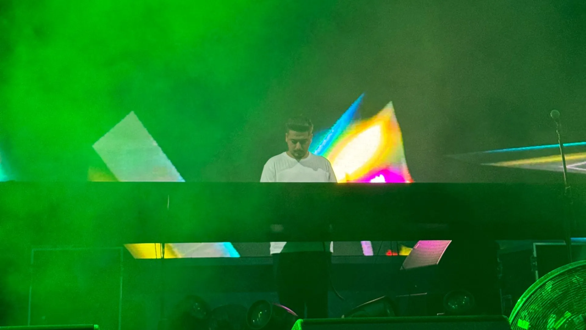 Fırat Gürel playing live behind the decks in green stage light — Cyprus